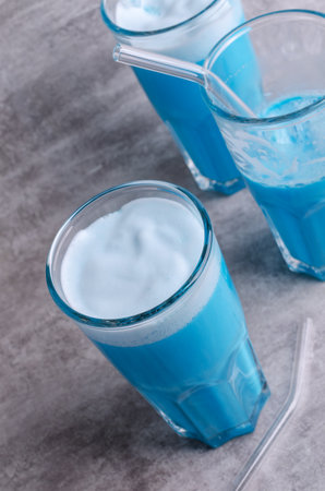Blue cream drink with foam in a glass on a gray background. selective focus.の写真素材