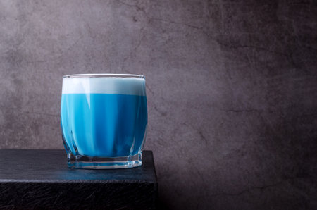 Blue cream drink with foam in a glass on a dark background. selective focus.の写真素材