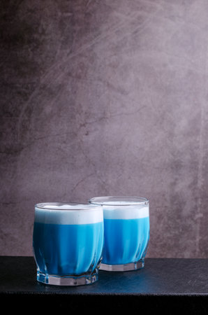 Blue cream drink with foam in a glass on a dark background. selective focus.の写真素材