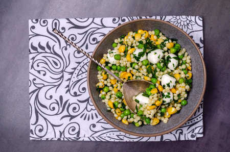 Salad of vegetables, pasta and mozzarella in a dish on a dark background. top view.の写真素材