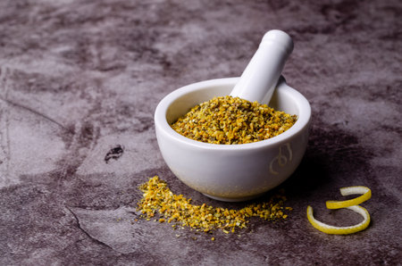 Seasoning lemon pepper in a ceramic mortar on a dark background. selective focus.の写真素材