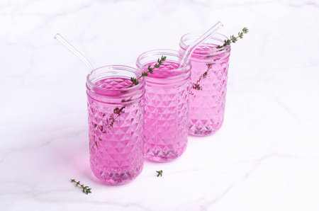 Pink drink with thyme in a glass on a light marble background. selective focus.の写真素材