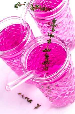 Pink drink with thyme in a glass on a light marble background. selective focus.の写真素材