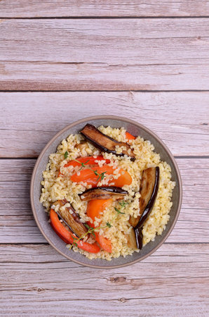 Wheat groats with slices of fried vegetables in a ceramic dish on a light background. selective focus.の写真素材