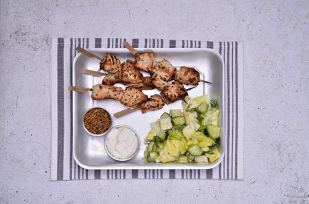 Fried slices of meat on wooden skewers. Raw vegetable salad, mustard and sour cream. view from above.の写真素材