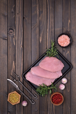 Raw meat fillet with spices in a metal plate on a dark wooden background. top view.の写真素材
