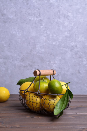 Ripe citrus fruits with leaves in a metal basket on a dark wooden background. Selective focus.の写真素材