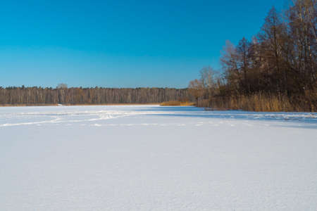 footprints in the snow, a frozen snow-capped lake and a blue skyの写真素材