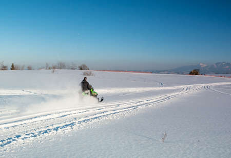 Polish Tatra Mountains, snowmobile and winter recreation, mountain peaks and a wall of mountain treesの写真素材
