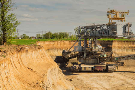 Industrial view of opencast mining quarry with machinery at work. Area has been mined for copper, silver, gold, and brown coal mine. Bucket-wheel excavator mining in a open pit brown coal mine.の写真素材