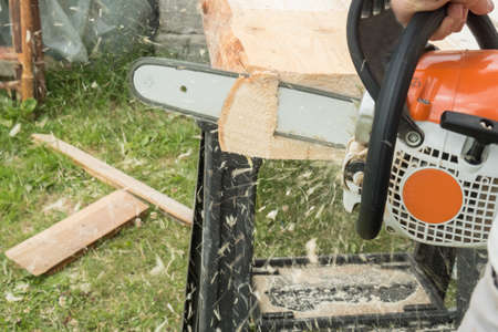 A construction worker cutting boards with a chainsaw in construction. focus on chainsawの写真素材