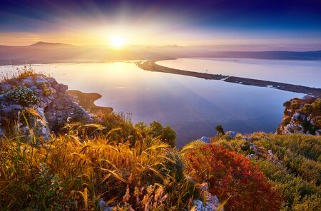 Amazing sunrise view with multicolored clouds from Navarino Castle. Romantic sunset on Voidokilia beach, Ionian Sea, Pilos town location, Greece, Europe. View of the ocean through the rocky shoreの写真素材