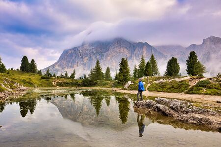 Man traveler traveling alone in breathtaking landscape of Dolomites. Amazing morning view of Limides lake. Splendid summer scene of Dolomiti Alps, Cortina d'Ampezzo, Falzarego pass, Italy, Europe. Beauty of nature concept background.の写真素材