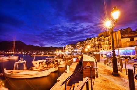 View from the waterfront of Calvi on the old town with historic buildings at night. Bay with yachts and boats. Luxurious marina and very popular tourist destination. Corsica, France, Europeの写真素材