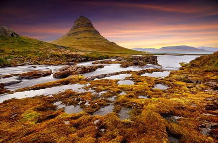 Colorful sunrise on Kirkjufellsfoss waterfall. Amazing morning scene near Kirkjufell volkano, Iceland, Europe. A famous tourist attraction near the city of Grundarfjordur. Travel concept background.の写真素材