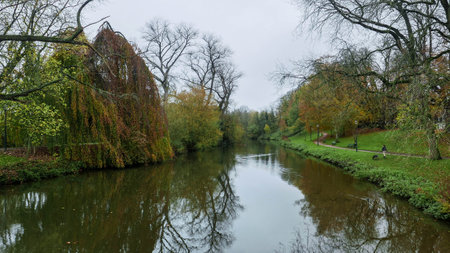 City park with a water canal and a lady walking the dogの写真素材