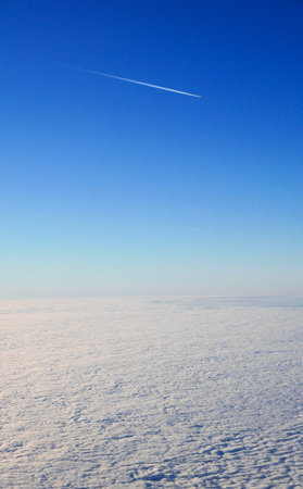 Airplane flying in the blue sky over white cloudsの写真素材