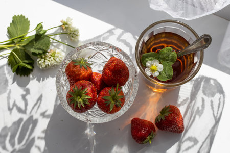 Cup of tea and strawberries on a white lace backgroundの写真素材