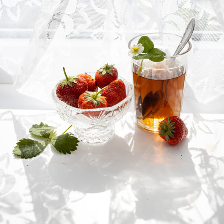 Cup of tea and strawberries on a white lace backgroundの写真素材