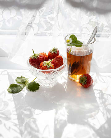 Cup of tea and strawberries on a white lace backgroundの写真素材