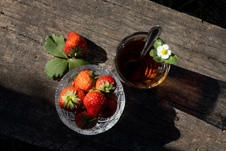 Cup of tea and wild strawberries on a wooden backgroundの写真素材