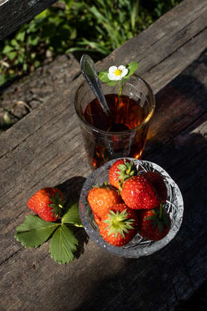 Cup of tea and wild strawberries on a wooden backgroundの写真素材