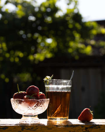 Cup of tea and wild strawberries on a wooden backgroundの写真素材