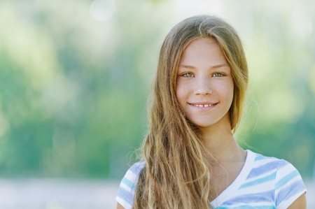 Beautiful smiling teenage girl in blue blouse, against green of summer park. Beautiful smiling teenage girl in blue blouse, against green of summer park.