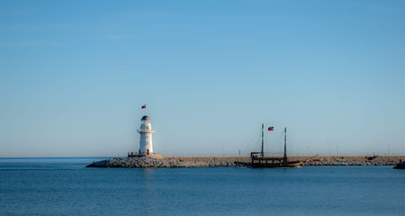 Panoramic view from the beach of the port with light house illuminated by the sunset sun