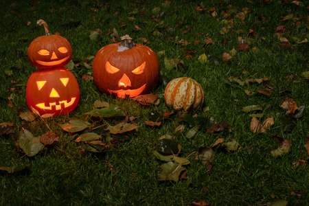 Halloween pumpkin head jack-o-lantern with scary evil faces and candles. Seasonal illuminated decoration. Looks scary, colorful neon light and dark background. Holidays.の写真素材