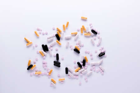 Yellow , black, white tablets and capsules lying on white background close-up. Omega 3, Multivitamins, Calcium, Antibiotics. Health. Immunity. Taking medication, pills. Nutritional supplement Copy spaceの写真素材