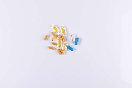 Yellow , blue, white tablets and capsules lying on white background close-up. Omega 3, Multivitamins, Calcium, Antibiotics. Health. Immunity. Taking medication, pills. Nutritional supplement Copy spaceの写真素材