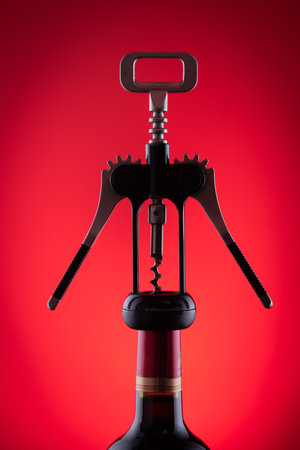 Modern corkscrew screwed in wine bottle on red backgroundの写真素材