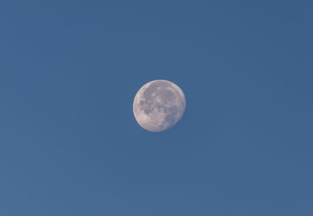 Full moon seen on the blue sky through camera lens