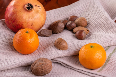 Pomegranate, selection of nuts , mandarins on waffer towel .