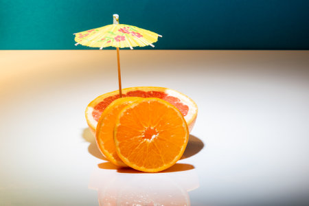 Red Grapefruit and clementines on white with cocktail umbrellaの写真素材