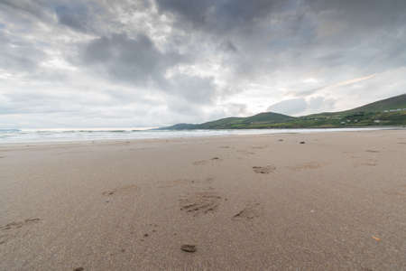 Overcast sky over sands of a beach with tide out. Mauntains in the distance.の写真素材