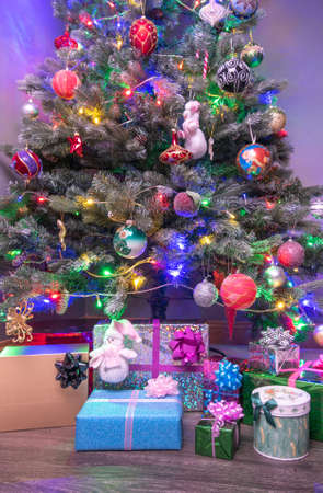 Boxes of presents under decorated artificial Christmas tree.の写真素材