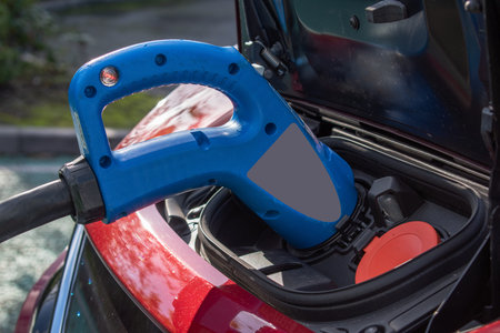 Electric car charging station. Close up of the power supply plugged into an electric car being...