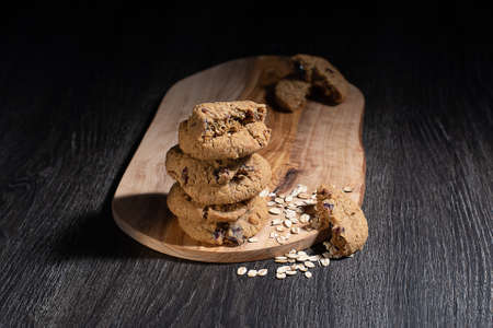 Oats cookies on wooden chopping board and black background.の写真素材