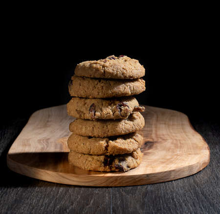 Oats cookies on wooden chopping board and black background.の写真素材