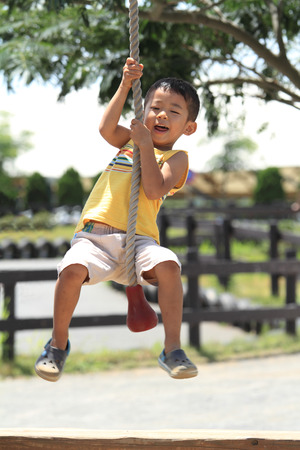 Japanese boy playing with Tarzan ropeの写真素材
