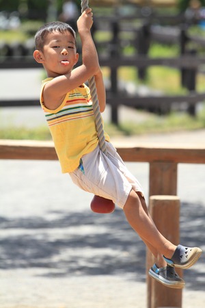 Japanese boy playing with Tarzan ropeの写真素材