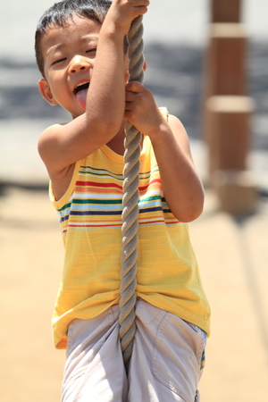 Japanese boy playing with Tarzan ropeの写真素材