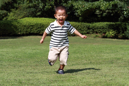 Japanese boy running on the grassの写真素材
