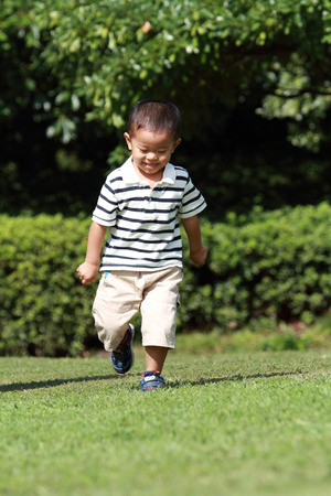Japanese boy running on the grassの写真素材