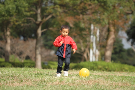 Japanese boy kicking a yellow ballの写真素材