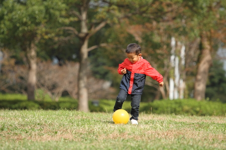 Japanese boy kicking a yellow ballの写真素材