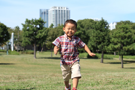 Japanese boy running on the grassの写真素材
