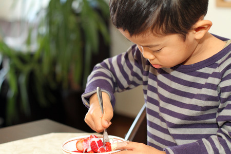 Japanese boy eating strawberryの写真素材